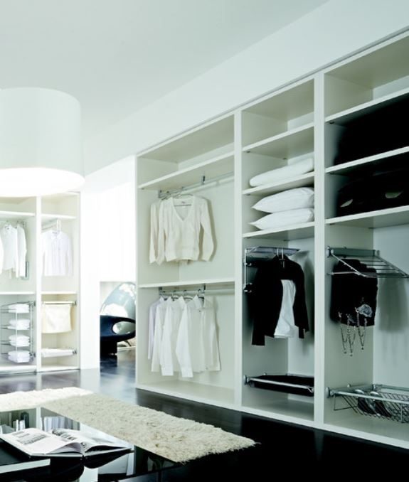 Un dressing moderne et bien organis&eacute; comprenant des &eacute;tag&egrave;res blanches avec une vari&eacute;t&eacute; de v&ecirc;tements soigneusement suspendus et dispos&eacute;s