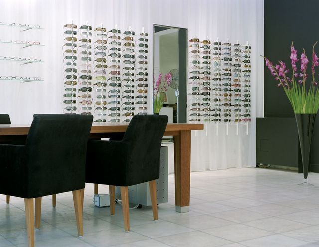 Un int&eacute;rieur de magasin d&rsquo;opticien moderne pr&eacute;sentant une gamme de montures de lunettes et d&rsquo;accessoires sur des pr&eacute;sentoirs muraux