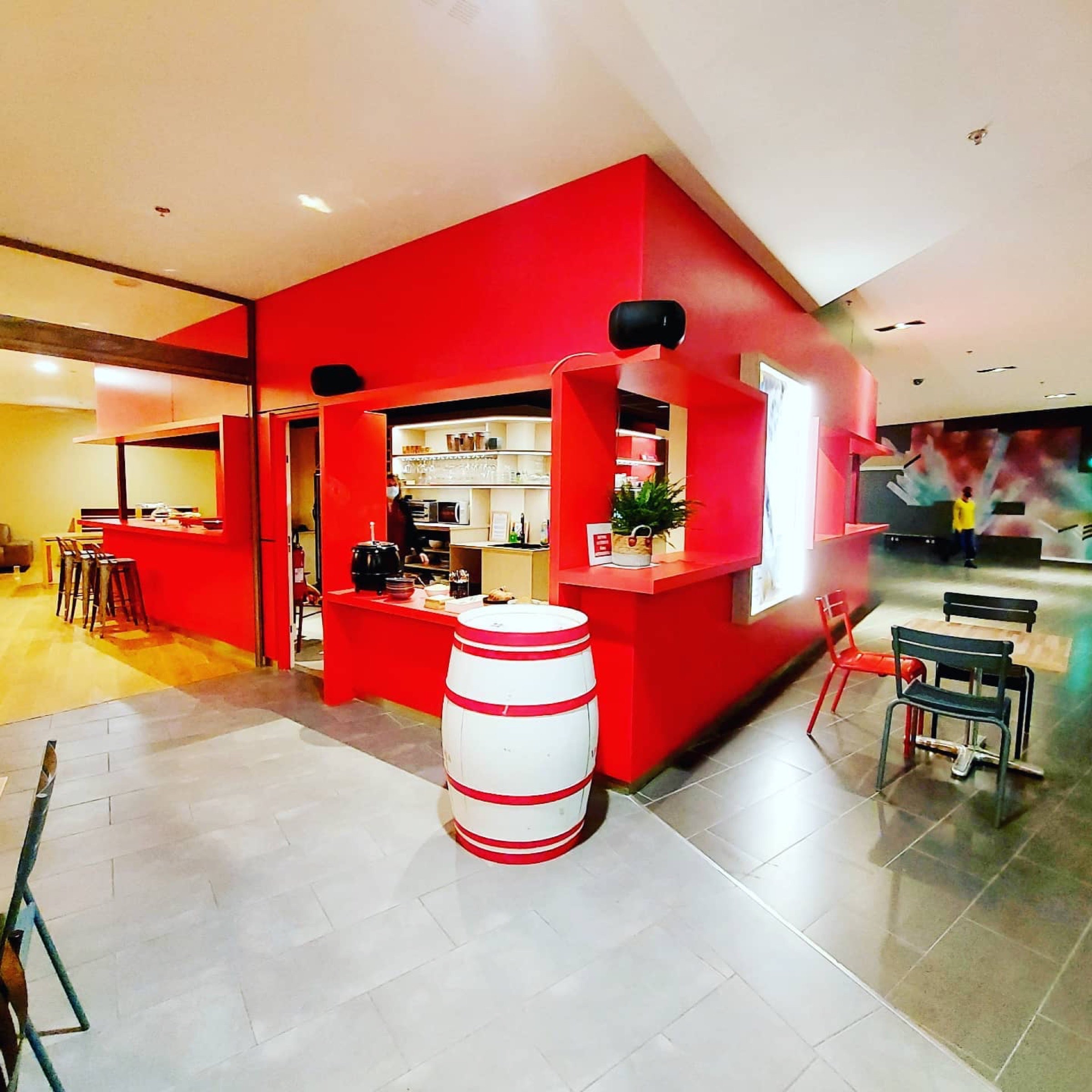 Un coin bar espace vibrant sur le thème rouge avec un design moderne, des tabourets de bar et un coin salon confortable.