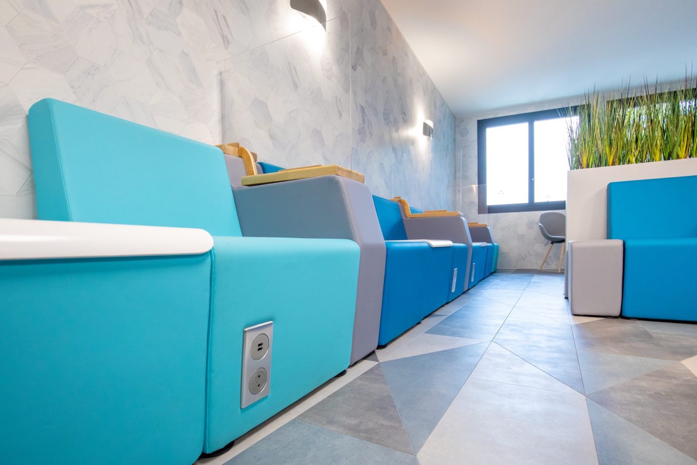 Un salon de p&eacute;dicure moderne et soign&eacute; avec des chaises bleues vibrantes et une atmosph&egrave;re relaxante, con&ccedil;u par un architecte d'int&eacute;rieur estim&eacute; &agrave; Pau.