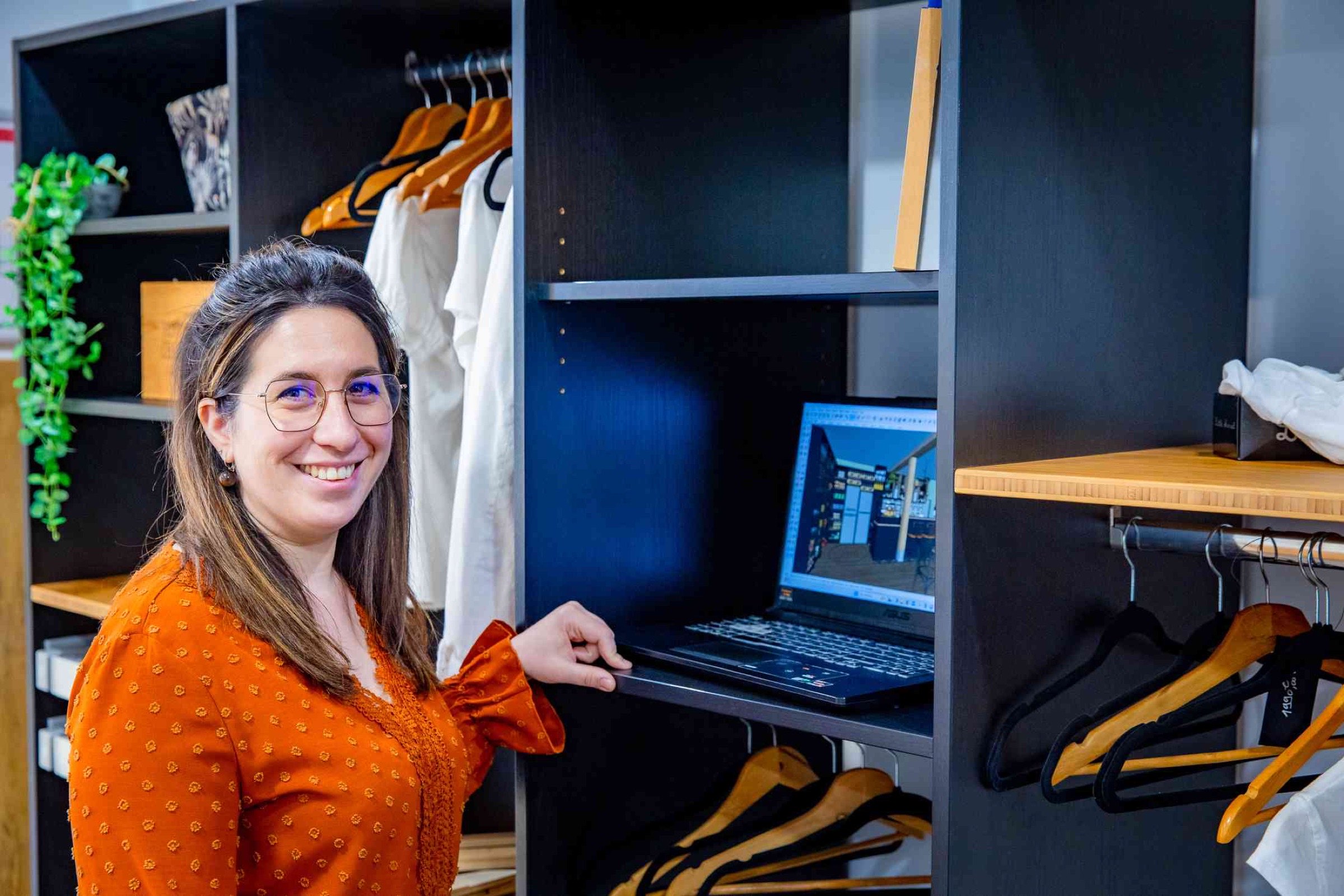 Une femme souriante travaillant sur un ordinateur portable sur un projet de dressing moderne et &eacute;l&eacute;gant