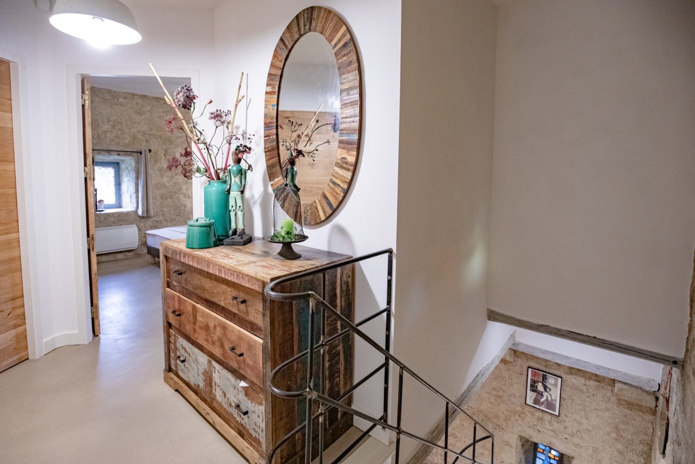 Un coin confortable et bien &eacute;clair&eacute; d'une maison, con&ccedil;u par un architecte d'int&eacute;rieur &agrave; tarbes, comprend une commode rustique en bois orn&eacute;e de vases d&eacute;coratifs et de fleurs, &agrave; c&ocirc;t&eacute;