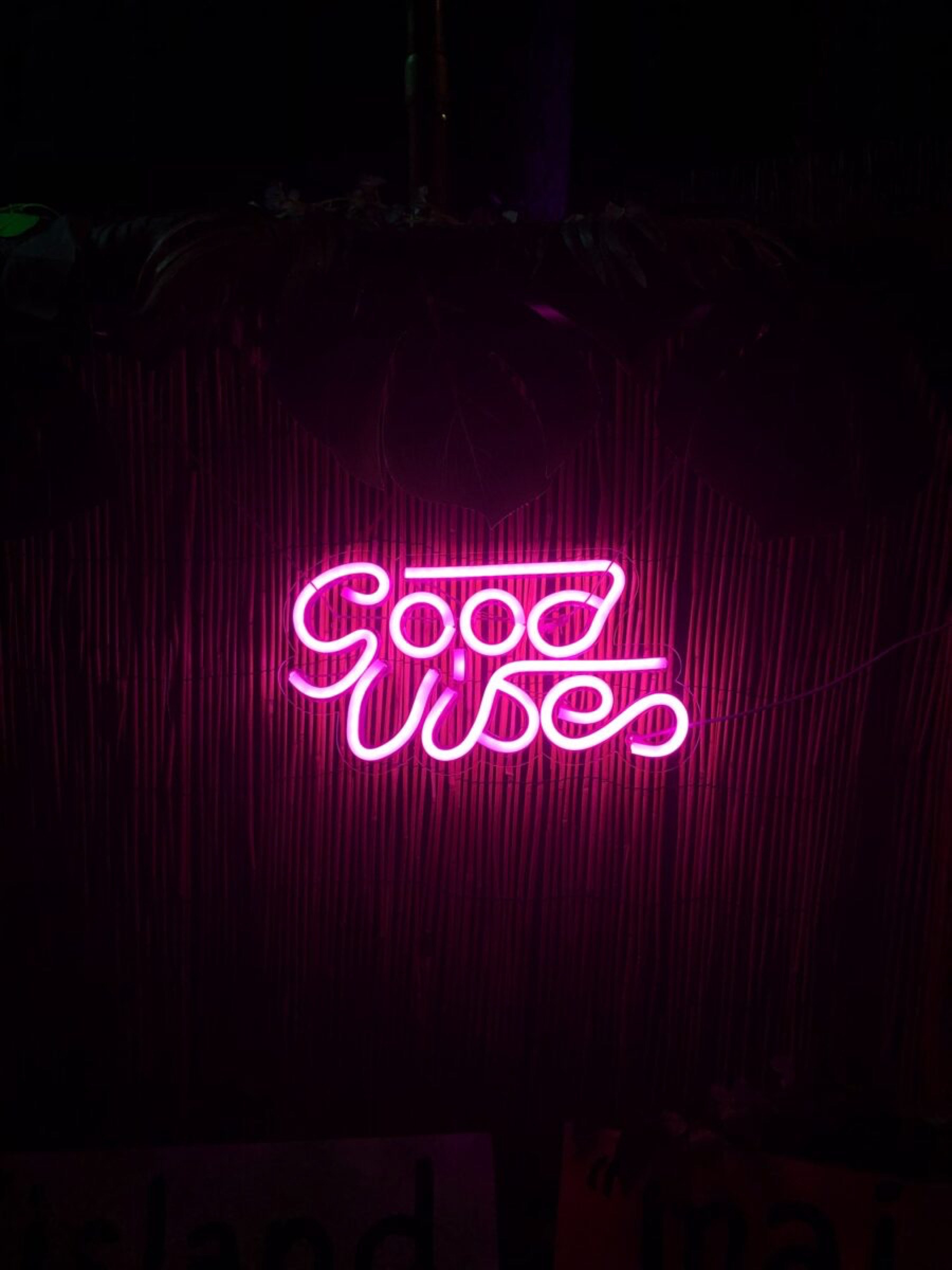 Enseigne n&eacute;on con&ccedil;ue par un architecte d'int&eacute;rieur &agrave; Tarbes, d&eacute;gageant une ambiance tropicale avec les mots "good vibes" sur fond bambou.