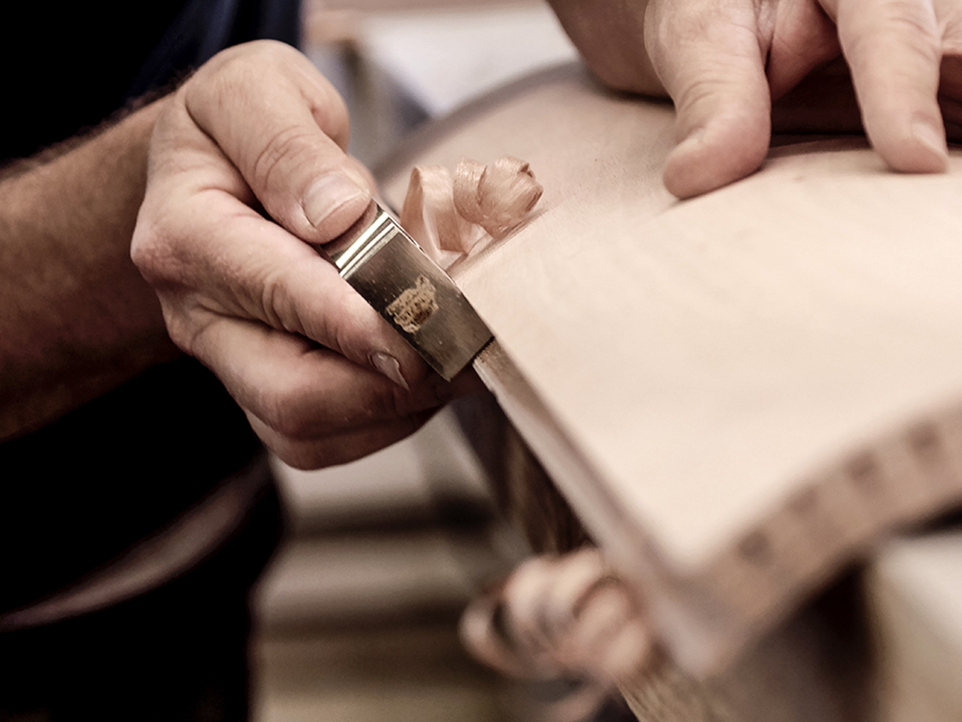 La précision de l'artisanat : des mains ciselant soigneusement le bois dans un atelier, mettant en valeur l'art du travail du bois.