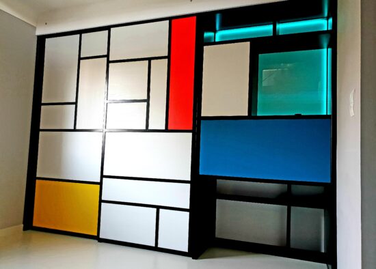 Un séparateur de pièce moderne au design inspiré de Mondrian, présentant des formes géométriques aux lignes noires audacieuses avec des panneaux de couleurs primaires et du blanc, parfait pour un architecte d'intérieur à Tarbes cherchant à s'intégrer