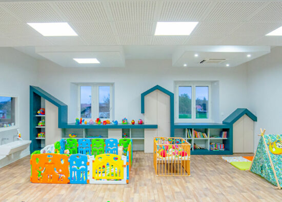 Une aire de jeu vive et colorée pour l'enfance avec des étagères en forme de maison, des zones de rangement de jouets et un coin lecture douillet.