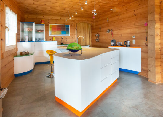 Un bureau à domicile lumineux et moderne avec des armoires blanches élégantes, un bureau incurvé et des touches de couleurs vives dans une pièce confortable lambrissée, inspirée de la palette de Mondrian.