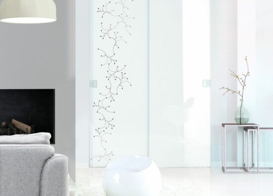 Un salon moderne doté d'une porte en verre dépoli aux motifs élégants, d'un canapé gris confortable, d'une chaise blanche artistique visible à travers l'embrasure de la porte et d'éléments de décoration chics dont un vase blanc avec des branches et un
