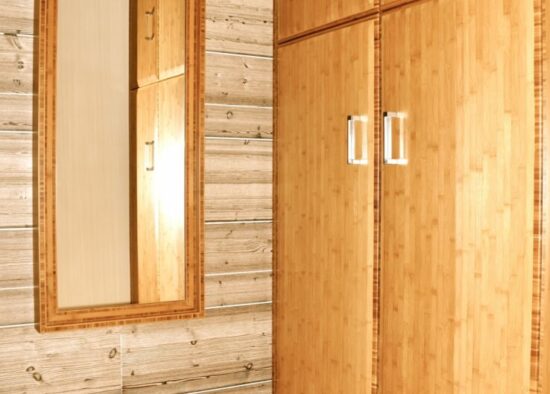 Un miroir en pied monté sur des planches de bois à côté d'une armoire en bois assortie à portes fermées, présentant un agencement sur mesure de style tarbais.