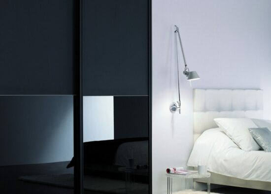 Chambre minimaliste moderne avec une grande armoire coulissante, des meubles sur mesure, une lampe de chevet élégante sur un lit d'un blanc éclatant et une palette de couleurs sereine.