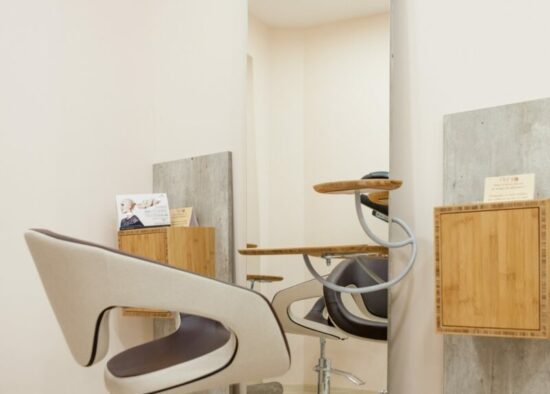 Un espace salon de coiffure moderne doté d'une chaise épurée, d'un grand miroir et d'une décoration minimaliste aux éclairages subtils, conçue par un architecte d'intérieur à Tarbes.