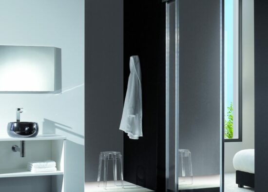 Une salle de bain épurée et moderne au design minimaliste noir et blanc signée par un architecte d'intérieur à Tarbes, comprenant une vasque et un espace douche vitré éclairé par la lumière naturelle.