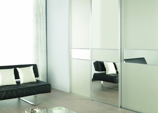 Salon moderne et minimaliste conçu par un architecte d'intérieur à Tarbes, comprenant un élégant canapé noir, des portes de placard coulissantes en miroir et une table basse en verre sur un parquet en bois.