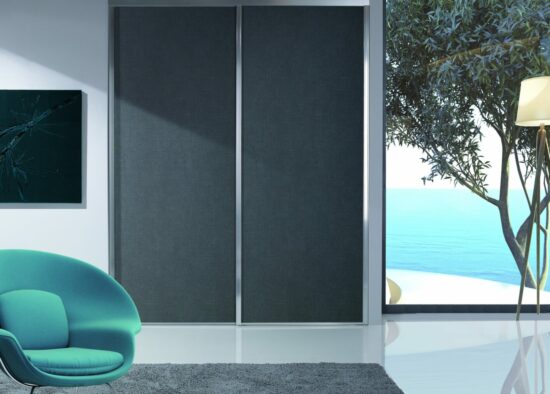 Salon minimaliste moderne avec vue sur l'océan, comprenant un élégant fauteuil turquoise, un lampadaire élégant, un tapis gris foncé et des portes coulissantes menant à un paysage marin serein. Inclusif est un