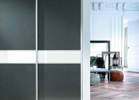 Des portes d'armoires coulissantes modernes au design épuré, contrastées avec un intérieur de pièce élégant, présentant un mélange harmonieux de fonctionnalité et d'élégance, complètent parfaitement l'esthétique de la « cuisine sur mesure à Tarbes ».