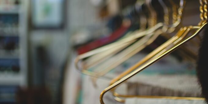 Des cintres dorés alignés sur un porte-dressing dans une boutique, attendant patiemment d'afficher les dernières tendances de la mode.
