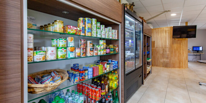 Une sélection soigneusement arrangée de snacks et de boissons sur les étagères d'une épicerie de village moderne, bien éclairée, redynamise le village.