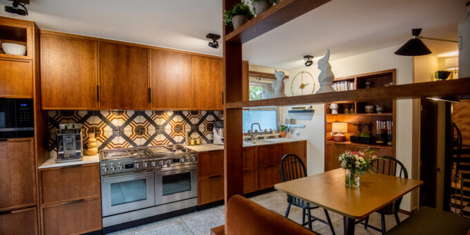 Une cuisine cosy et chaleureusement éclairée, récemment rénovée pour redonner l'âme d'une maison des années 60-70, avec des armoires en bois, des électroménagers en acier inoxydable, un dosseret élégant et un