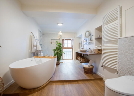 Une salle de bain sereine et moderne avec une baignoire îlot, du parquet, des murs carrelés blancs et une décoration de bon goût créant une atmosphère harmonieuse dans le cadre de l'agencement maison.